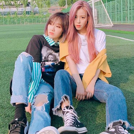 Khan (duo group of Minju and Euna) sitting in a soccer field